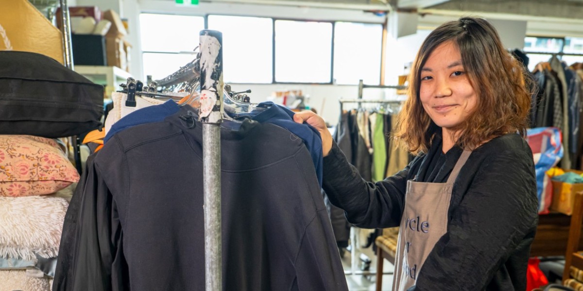 A volunteer at Mary Potter Hospice hanging used clothes on a rack