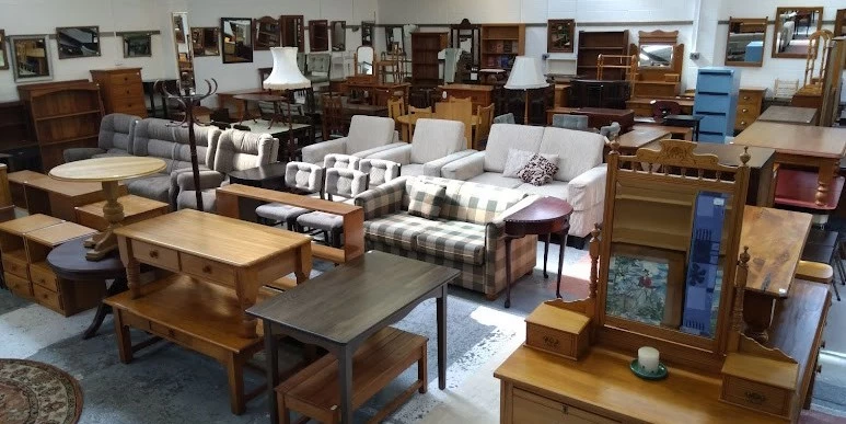 A wide selection of wooden tables, coffee tables, couches, and mirrors displayed at Weirs Furniture in Dunedin