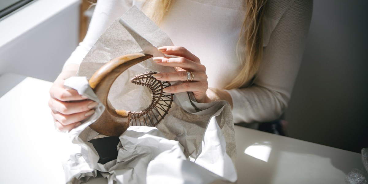 A woman wrapping a frafile home decor with a packing paper