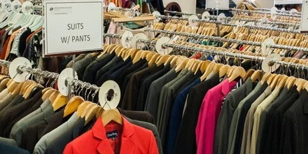 Rows of clothes rack with hanged suits and pants of different colors and styles