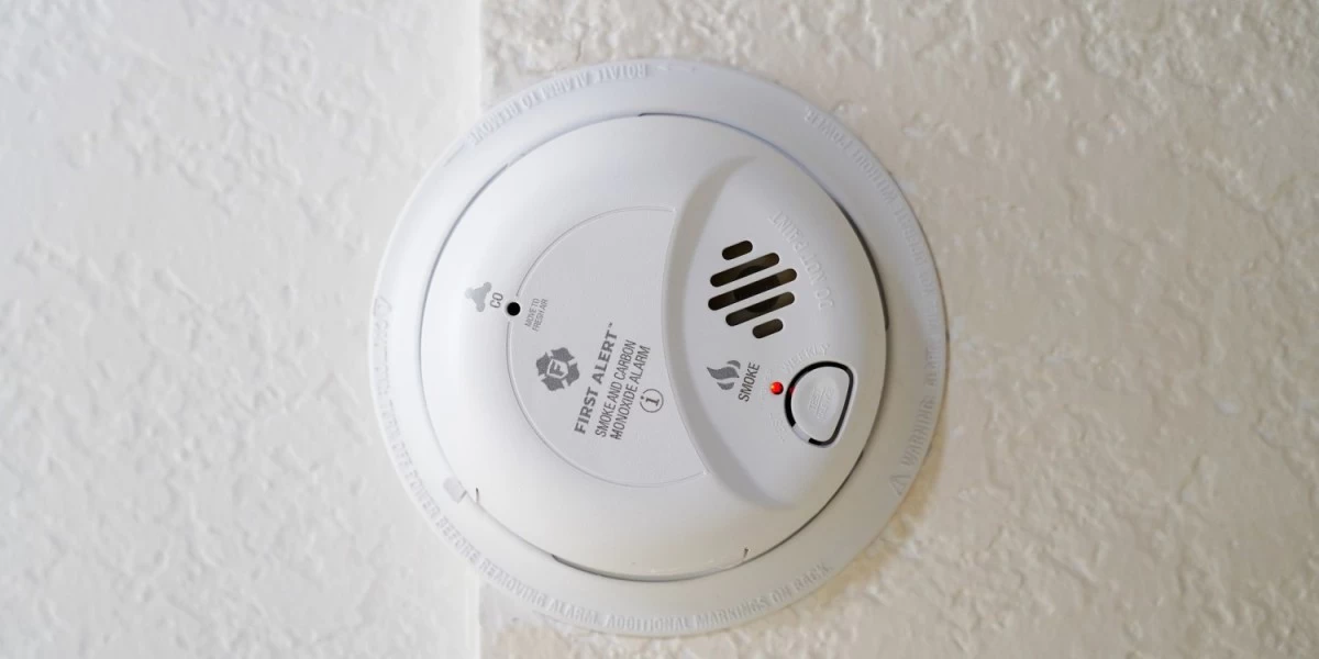 A smoke alarm with an old battery that is to be replaced with fresh one