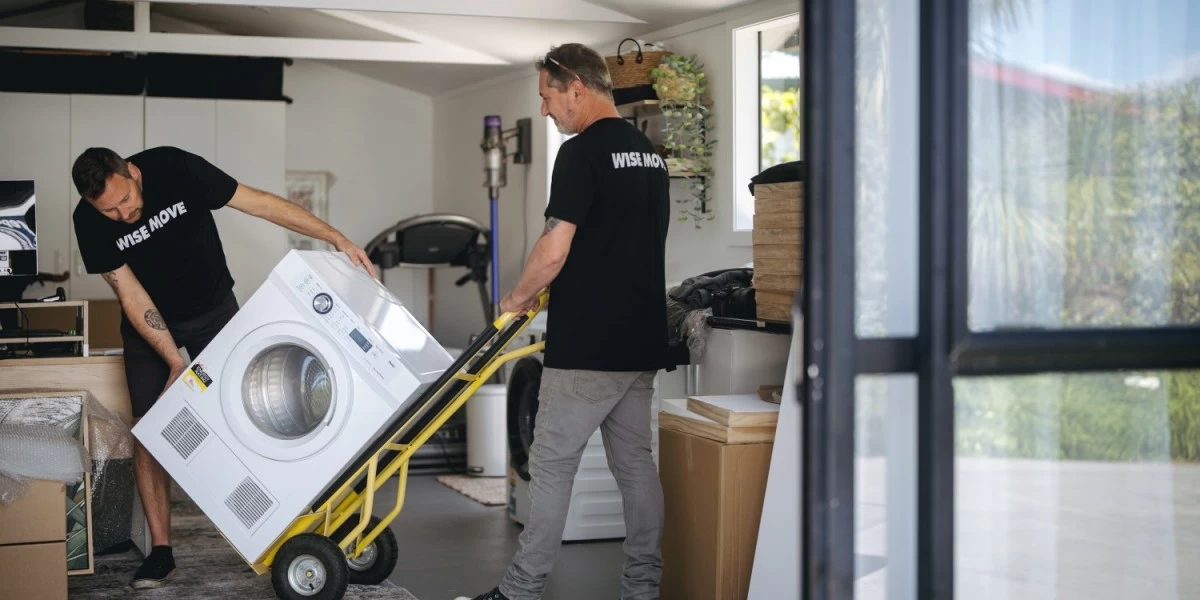 Two movers are seen carting a washer from a garage