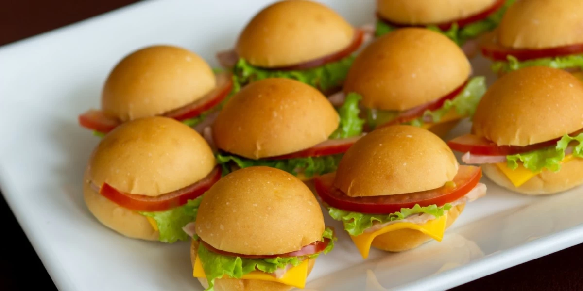 Ham and cheese sliders served in a white ceramic tray