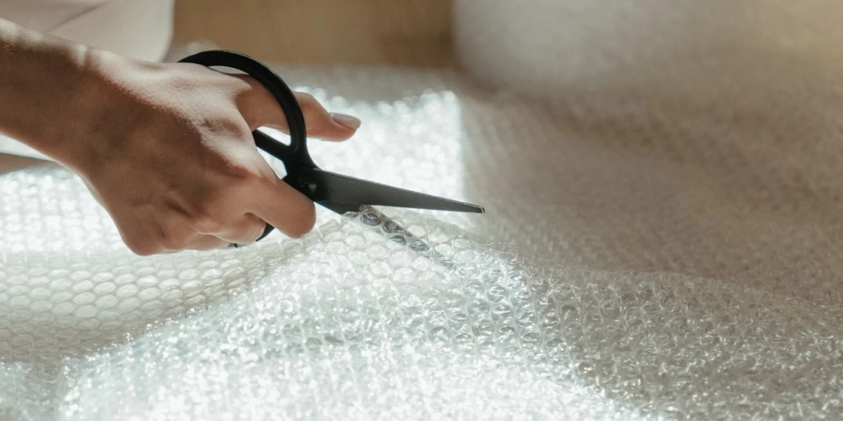 Bubble wrap being cut by a woman using a pair of scissors