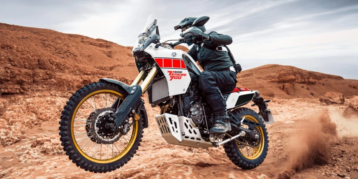 A man in full motorcycling gear riding a Yamaha Tenere 700 in an offroad