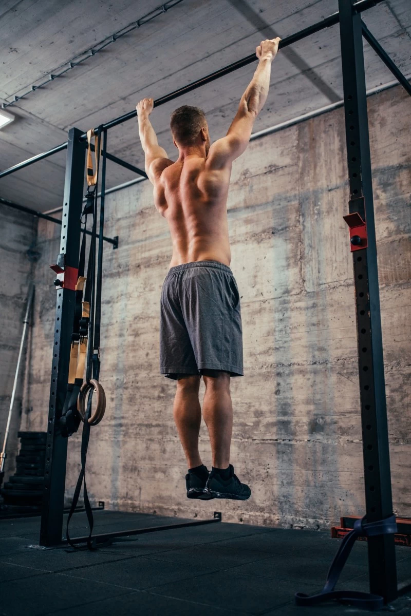 A man hanging on a pull-up station