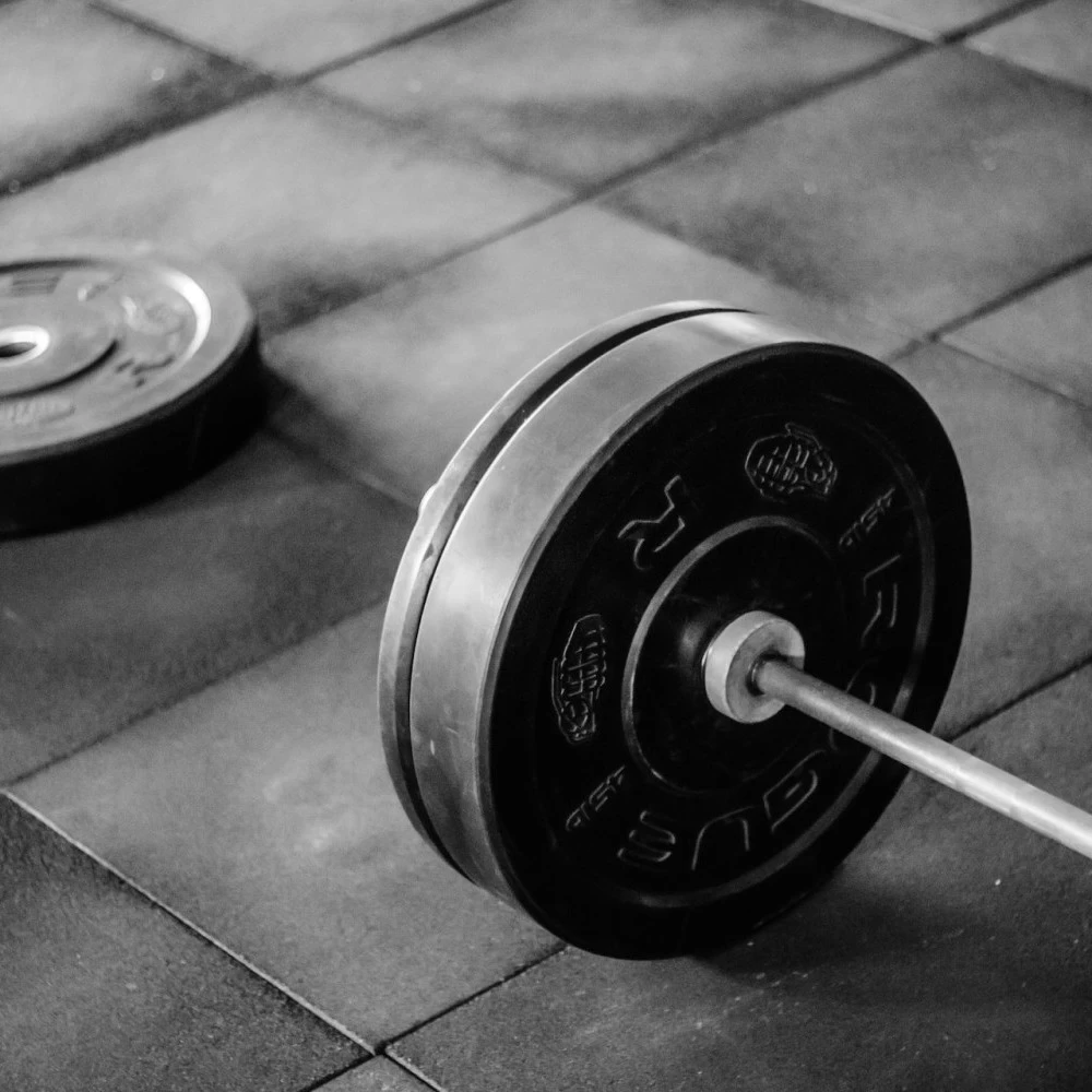 A loaded barbell sitting idle on the rubber floor at a gym