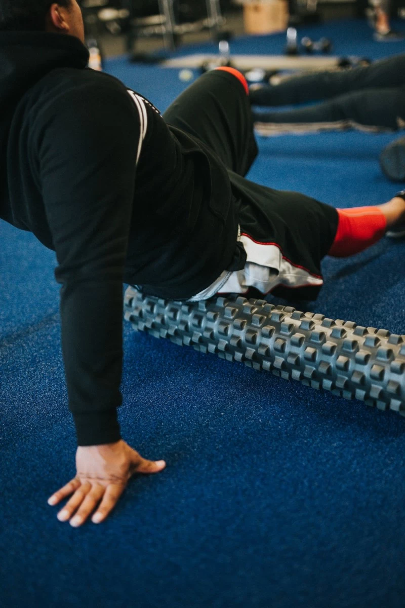 A man lying with a foam roller under his hips