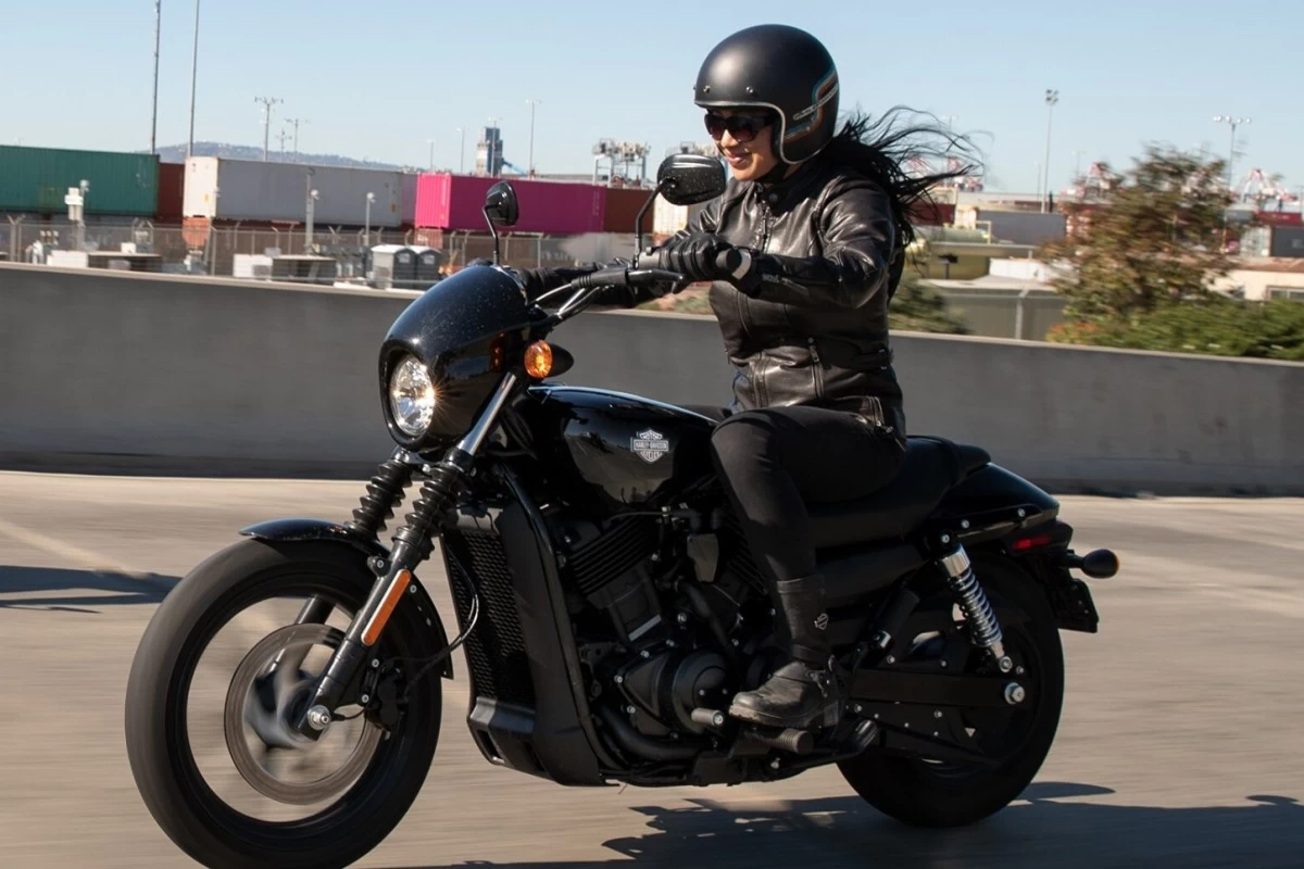 A lady riding a Harley Davidson Street 500 on paved road