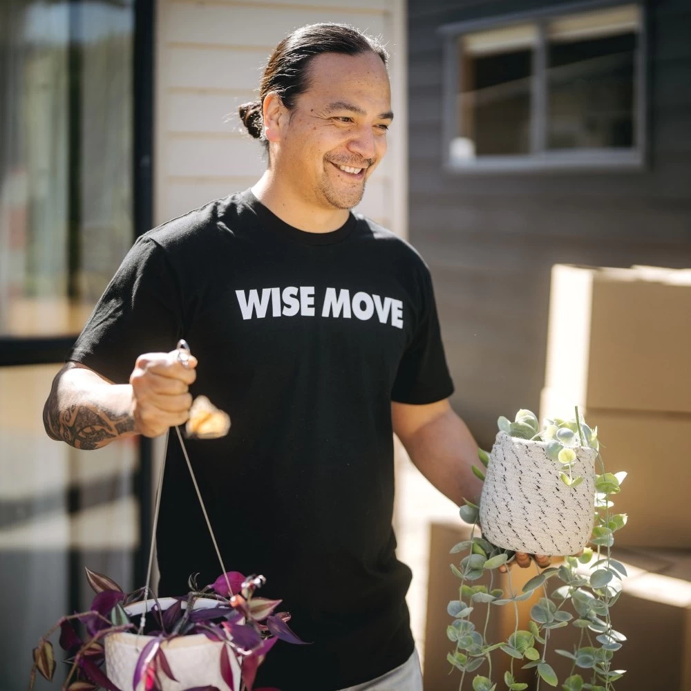 A mover carrying indoor plants in both hands while walking towards the moving truck