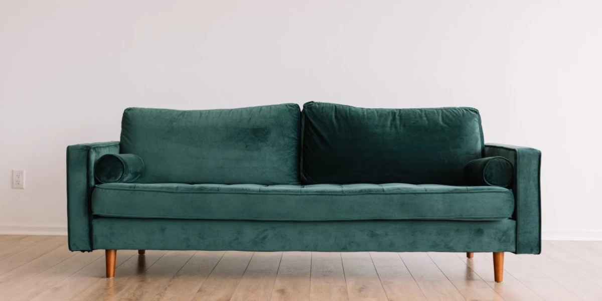 A green velvet 3-seater sofa sitting in a bright white room, perfect for upgrading the style of a lounge