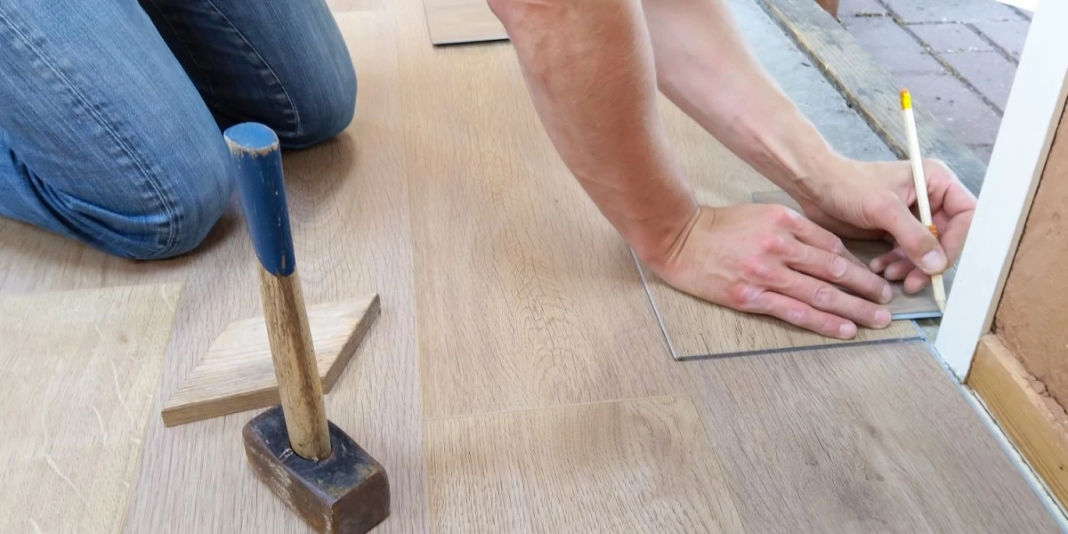 A man doing a floor renovation, replacing dirty carpets with wood tiles