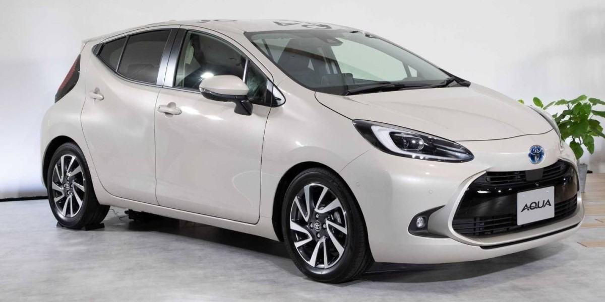 A white Toyota AquA, a hybrid electric vehicle from the Japanese automaker Toyota, equipped with a 1.5 L petrol engine and an electric motor