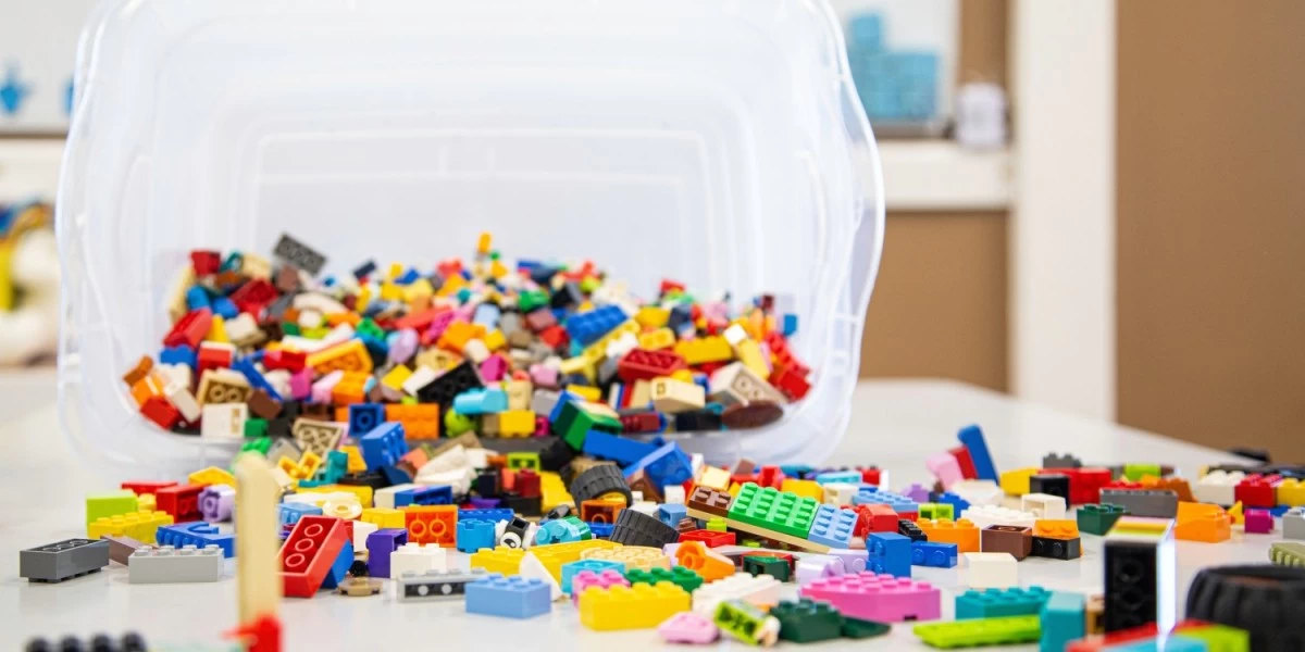 Box of multi-coloured Lego toys scattered across the floor