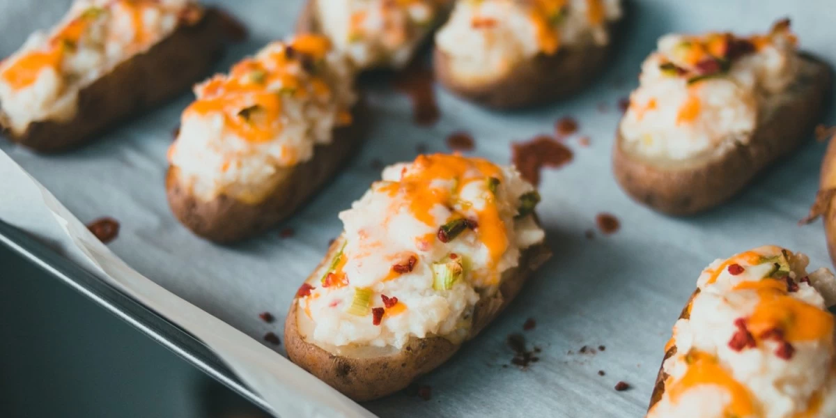 A tray of baked potatoes topped with cheese fresh from the oven