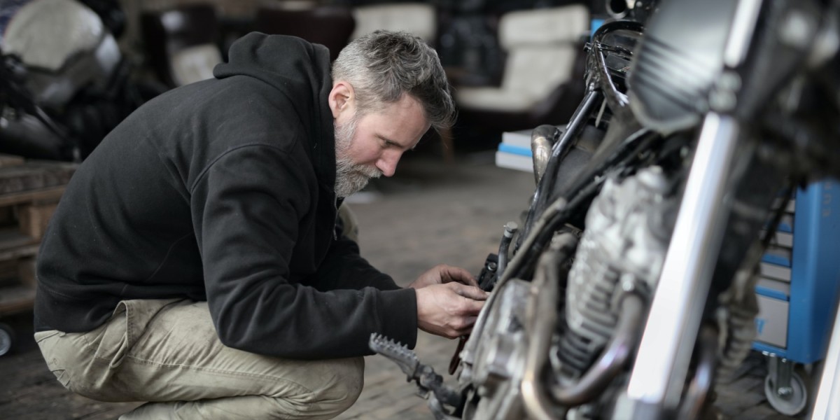 A man checking a motorcycle in a garage