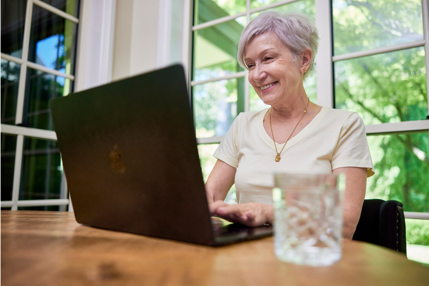 Elderly woman looking for a retirement village in Hamilton on her laptop