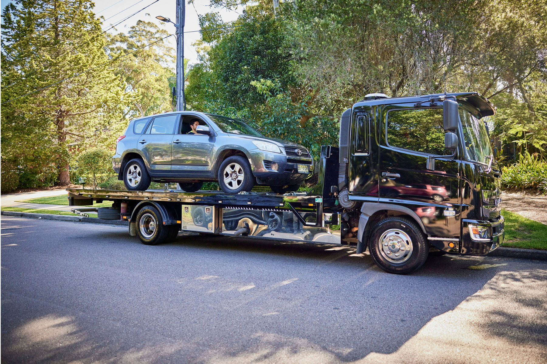 car transporter driving car onto the back of a transportation vehicle