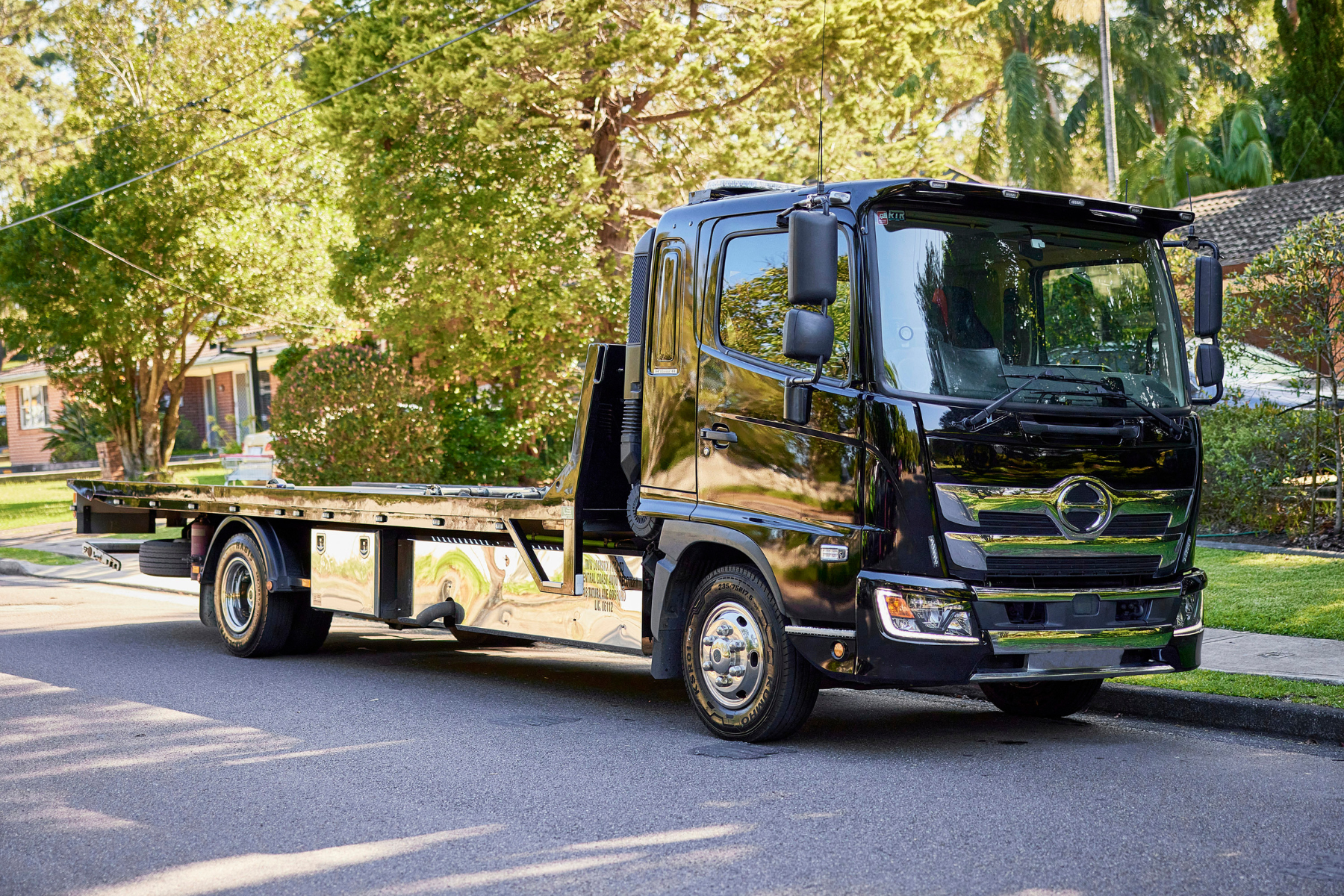 Empty flatbed tow truck parked on residential street ready for car transport