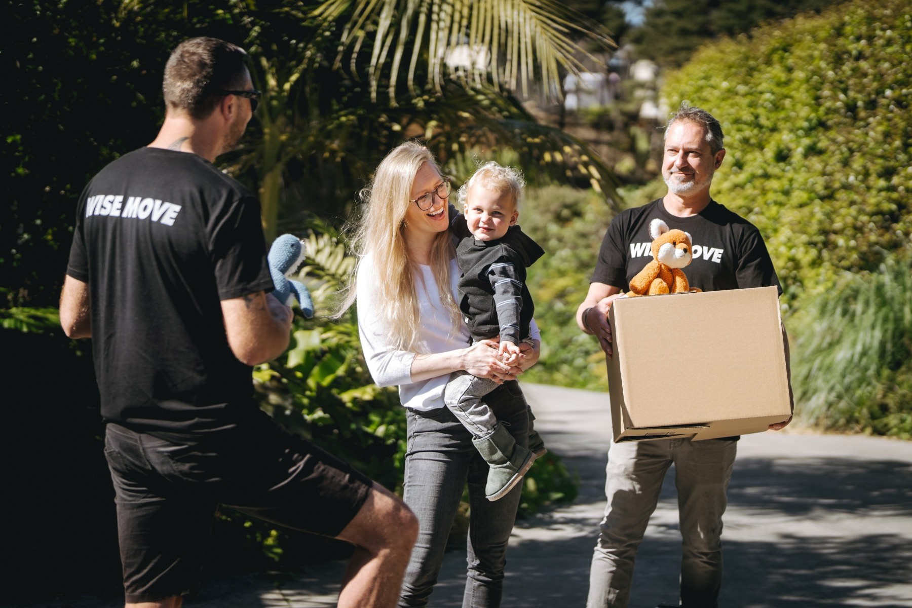 A lady carrying her toddler while happily talking to the movers she hired for her home move