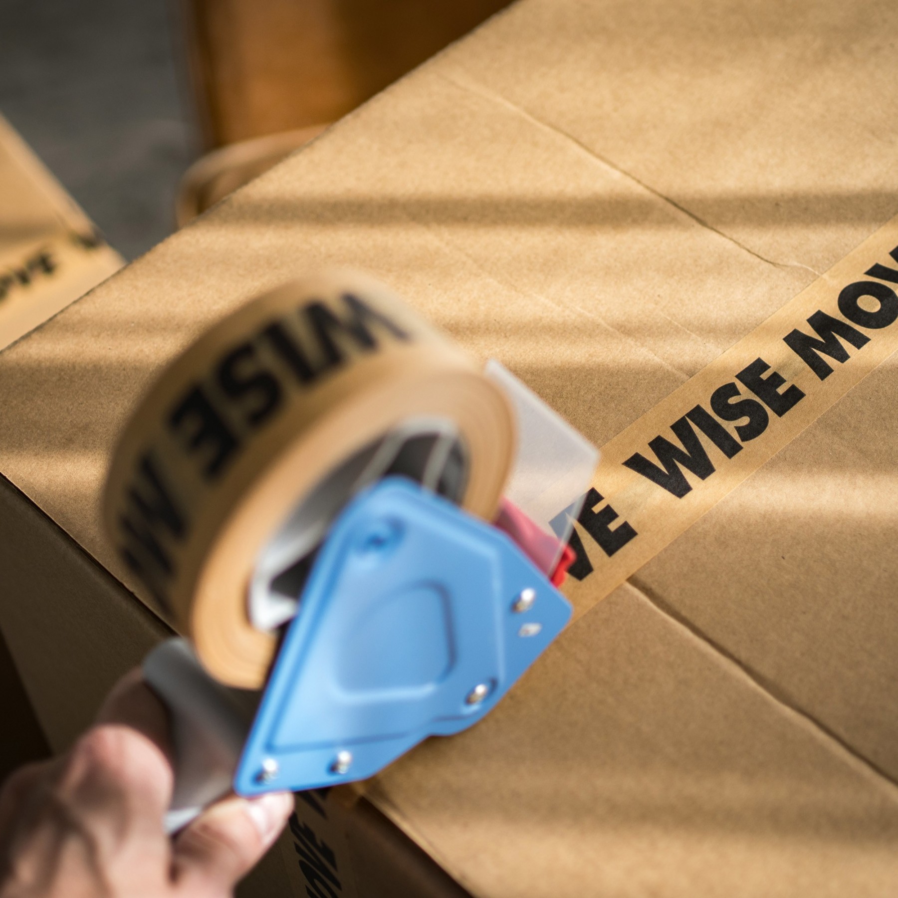 A woman packing a moving box and closing it with a packaging tape