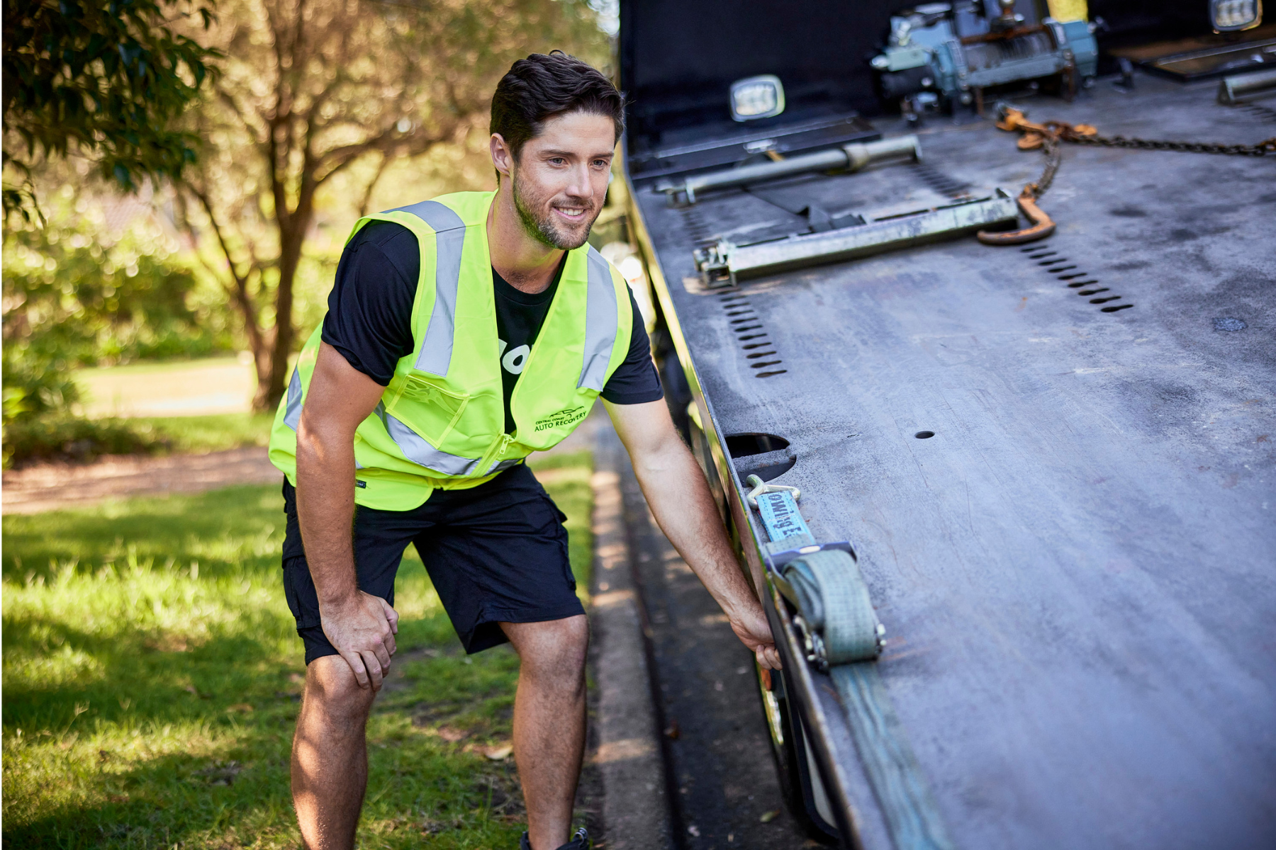 Vehicle transport worker preparing flatbed tow truck ramp