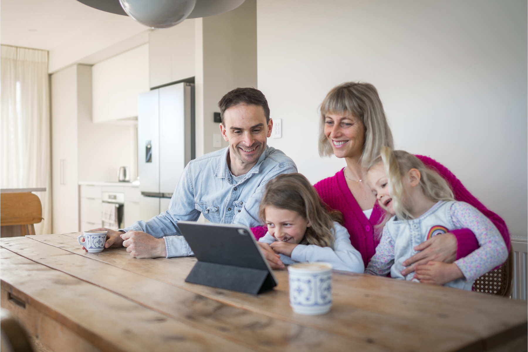 Parents and kids sitting at a dinner table researching childcare