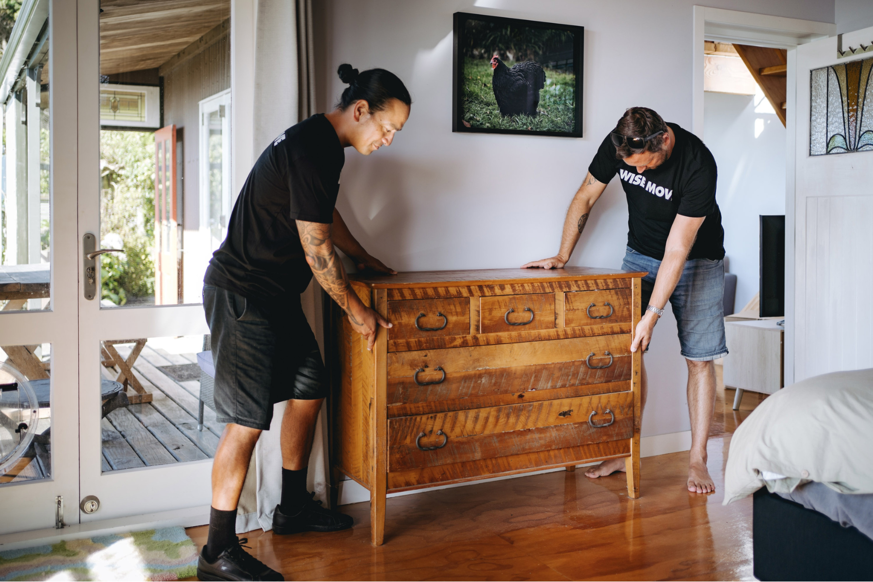 Wise Move movers carrying a wooden dresser from a bedroom during a student move