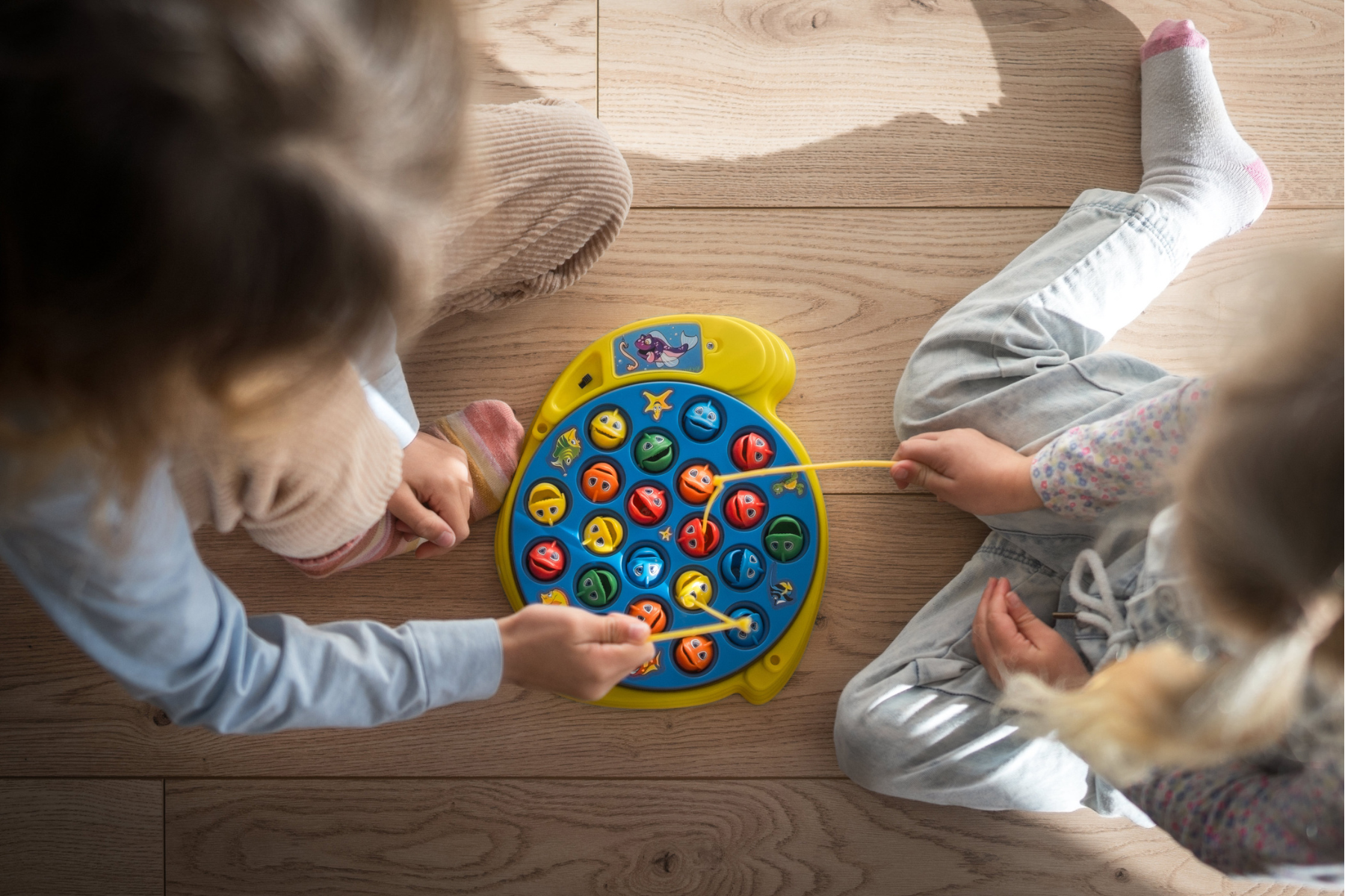 Children playing a fishing game together on the floor as part of early learning at home